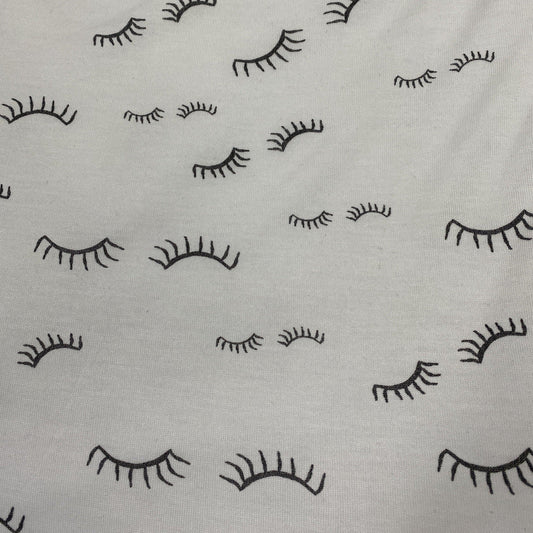 Nature's Fabrics white fabric featuring a black minimal closed eyelash pattern.