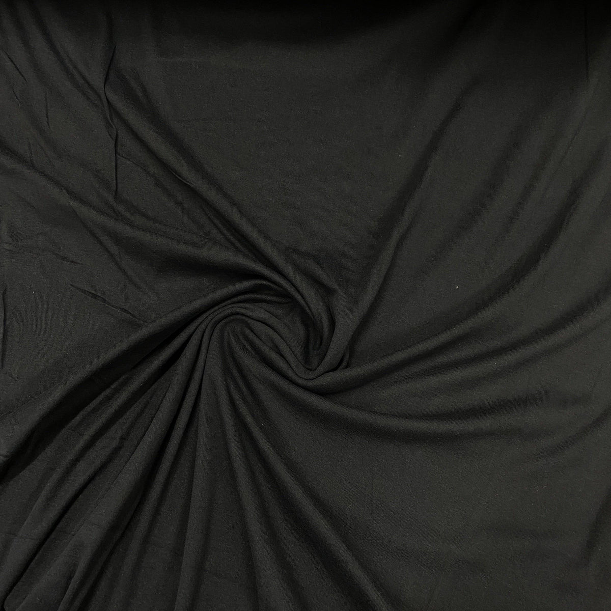 Black premium natural fabric by Nature's Fabrics, draped in a swirling spiral pattern.