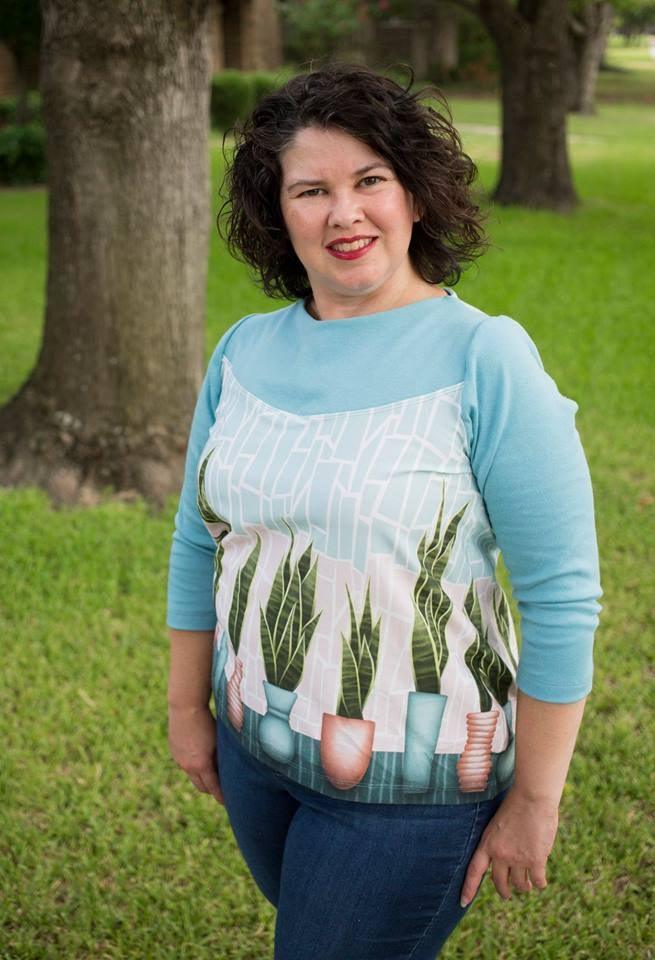 Woman wearing a Nature's Fabrics light blue top with a botanical plant print.