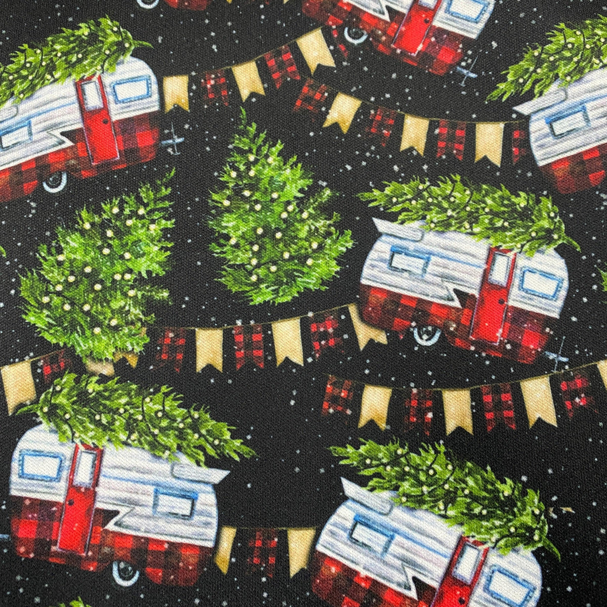 Nature's Fabrics holiday print with red campers, Christmas trees, and bunting on black.