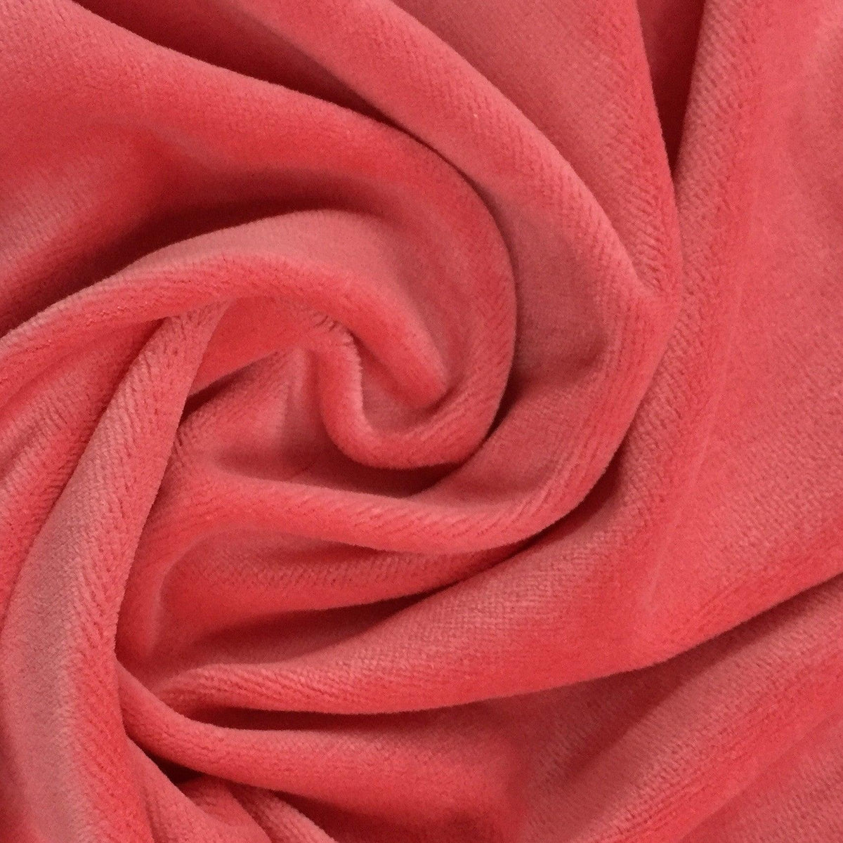 Close-up of swirled coral pink velvet fabric from Nature's Fabrics