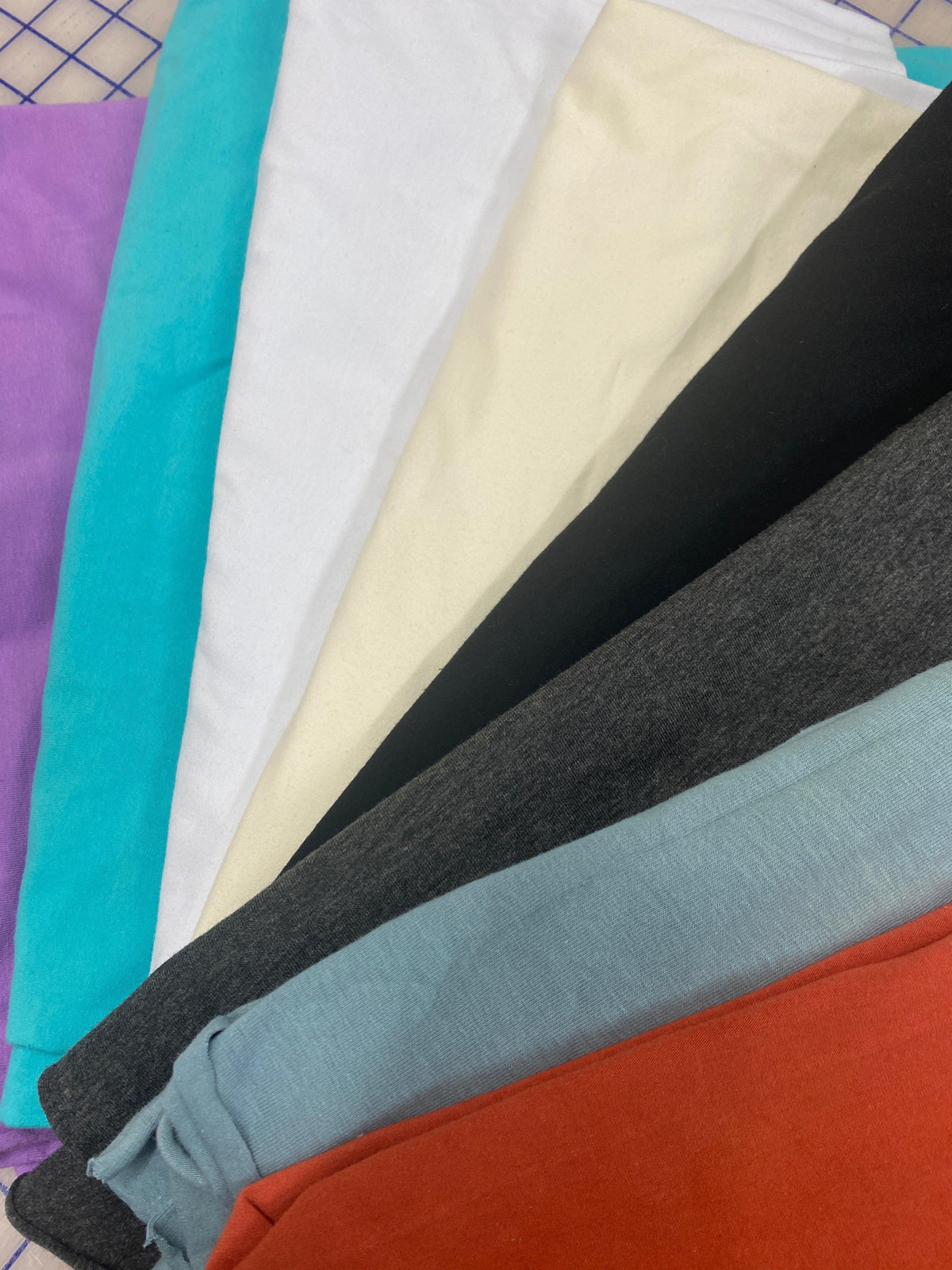 Variety of Nature's Fabrics colorful organic cotton fabric rolls in vibrant hues.