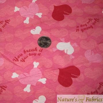 Pink Nature's Fabrics cotton with heart and bone patterns and a coin for scale.