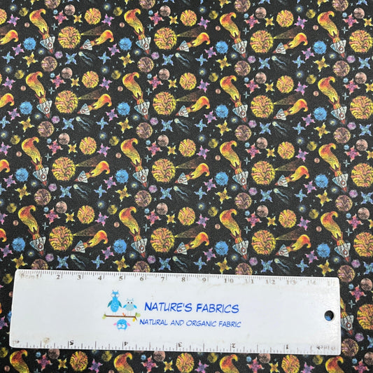 Nature's Fabrics cosmic print fabric with colorful birds and planets next to a ruler
