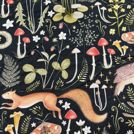 Nature's Fabrics organic cotton fabric with woodland patterns of a squirrel, mushrooms, and plants.