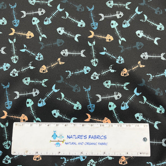 Nature's Fabrics dark grey fabric with a colorful fish skeleton pattern and a ruler for scale.