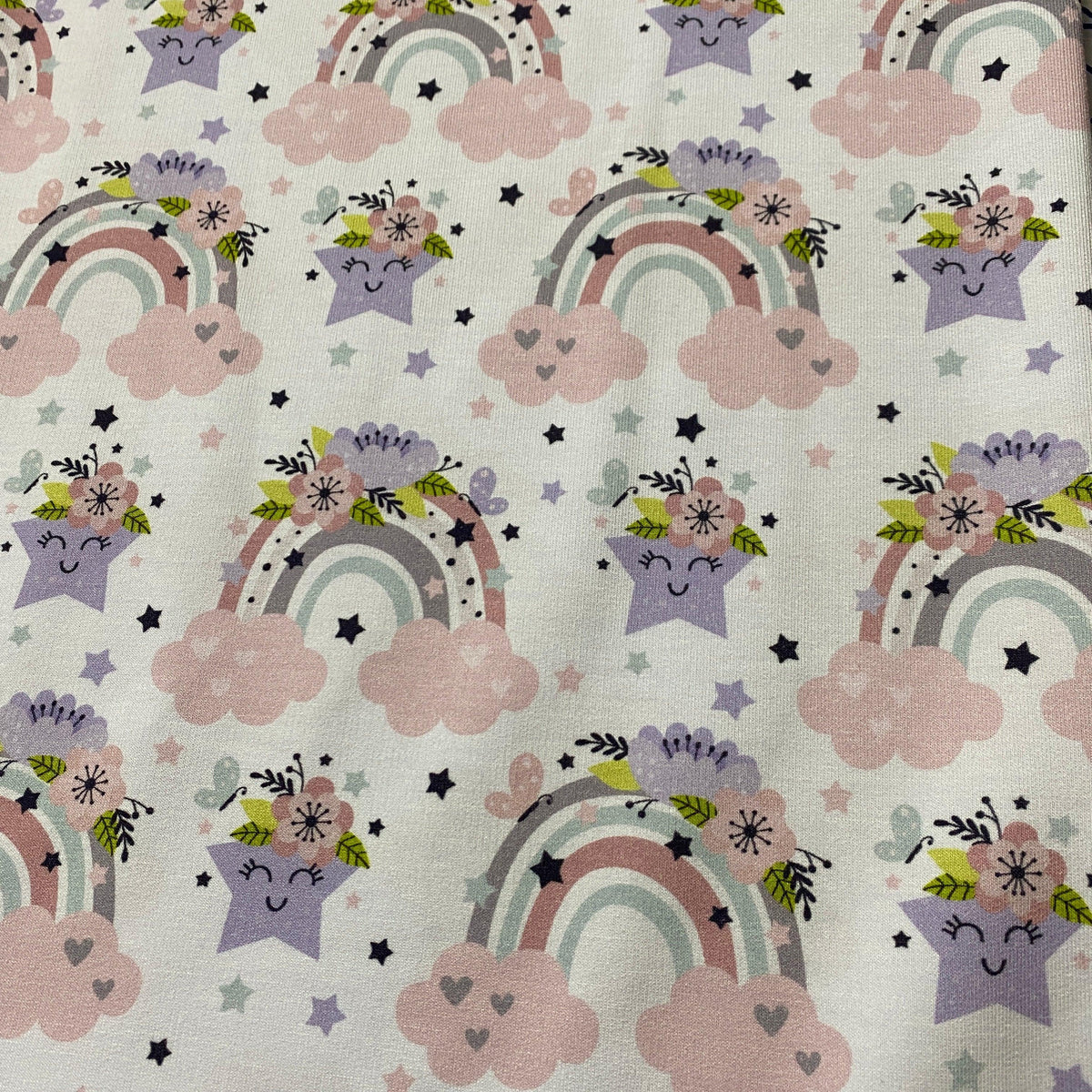 Nature's Fabrics organic cotton fabric with pastel rainbows, stars, and clouds pattern.