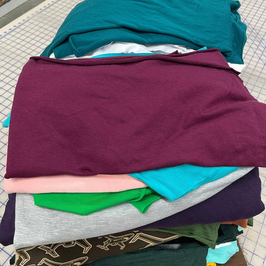 A stack of colorful Nature's Fabrics fabric remnants in various hues and textures.