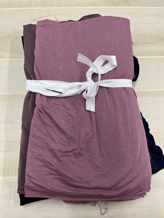 Stacked folds of mauve and dark purple Nature's Fabrics tied with a white ribbon.