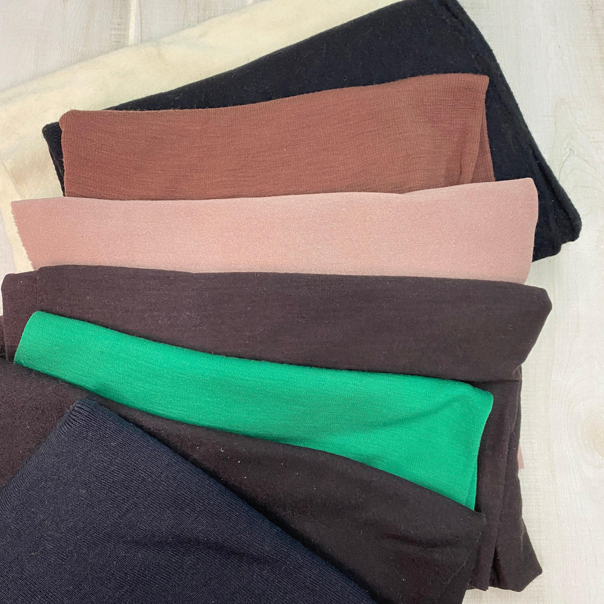 Stacked folds of Nature's Fabrics premium natural fabric in various colors.