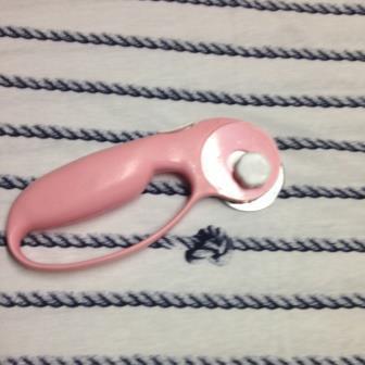 Nature's Fabrics pink rotary cutter for fabric on striped white textile