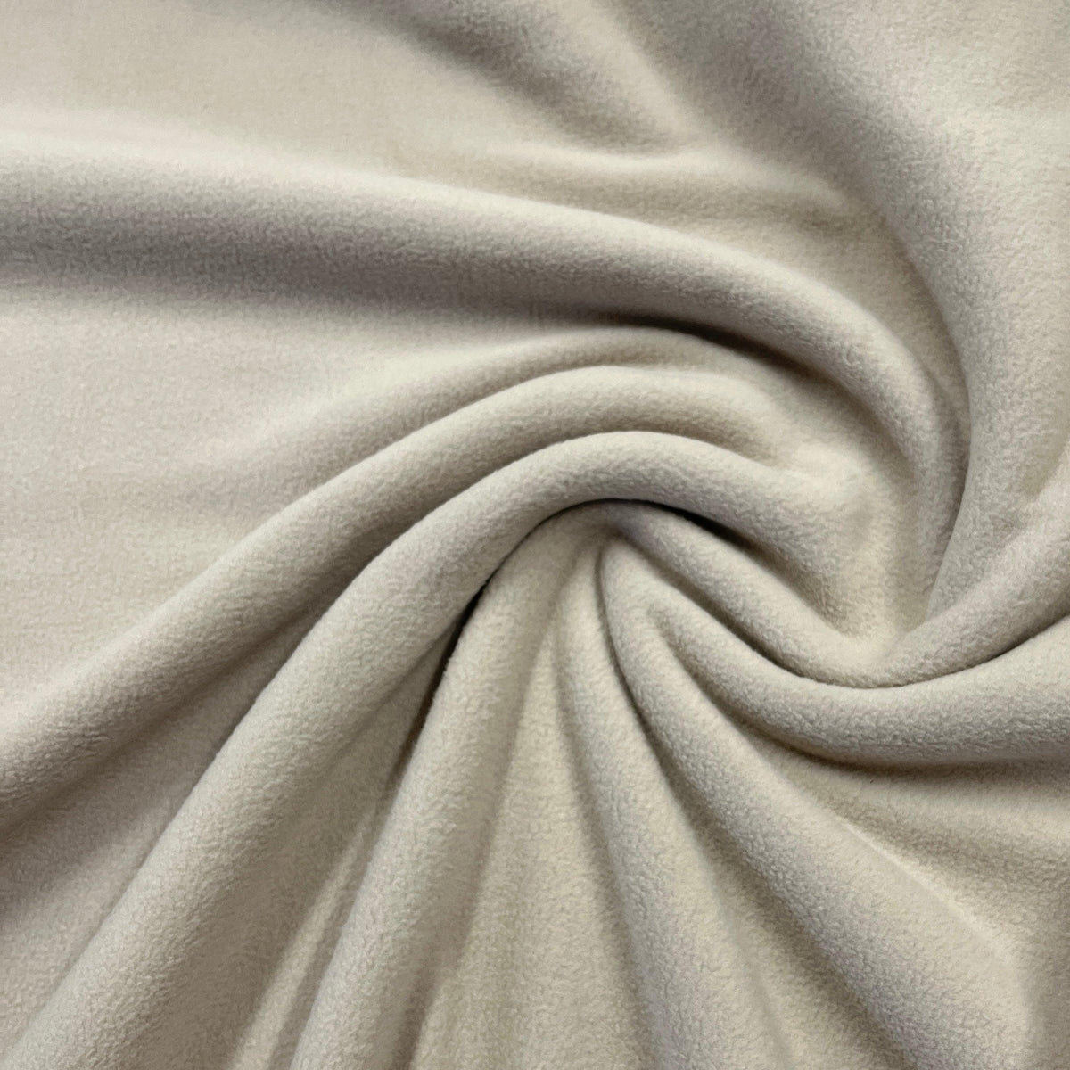 Close-up of soft, cream-colored Nature's Fabrics fleece material swirled into folds.