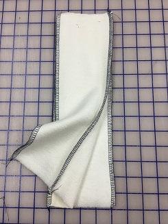 White Nature's Fabrics natural fabric strip with stitched edges on a blue grid cutting mat