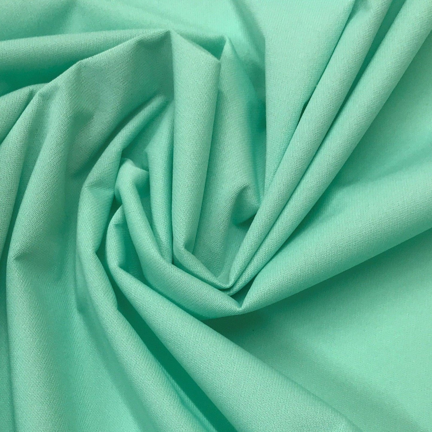 Close-up of mint green natural fabric draped in folds from Nature's Fabrics.