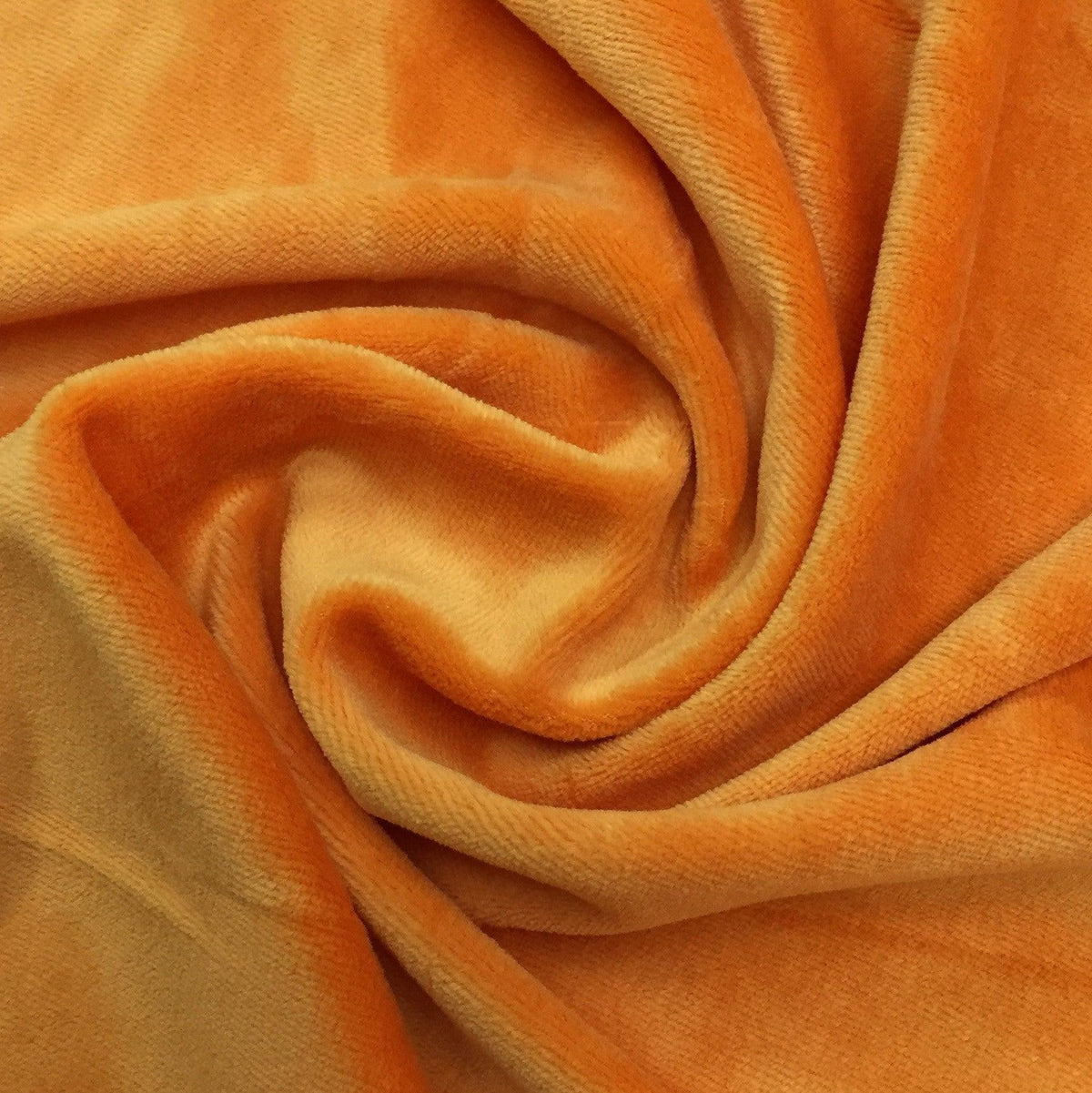 Orange velvet fabric draped in a swirl by Nature's Fabrics