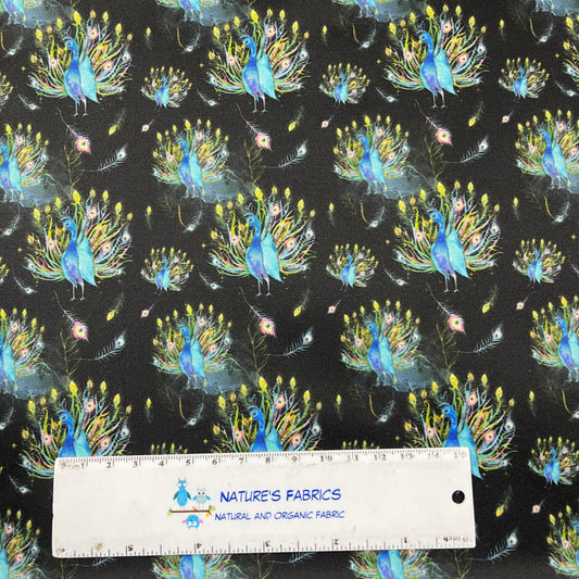 Nature's Fabrics organic cotton fabric featuring a vibrant peacock print on a black background.