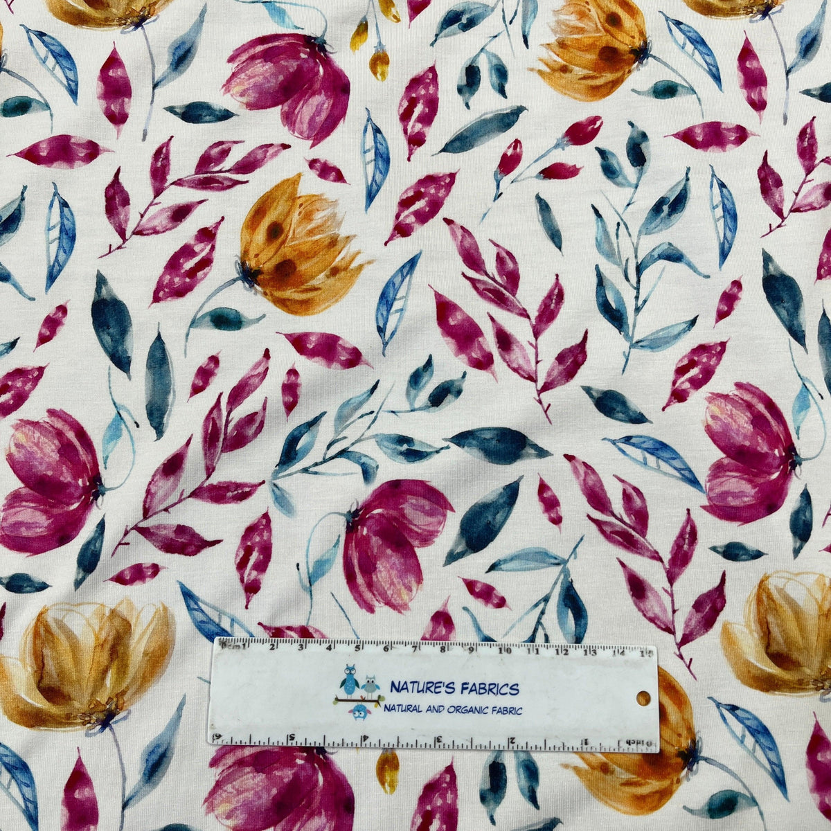 Nature's Fabrics organic fabric with a pink, yellow, and blue watercolor floral pattern.