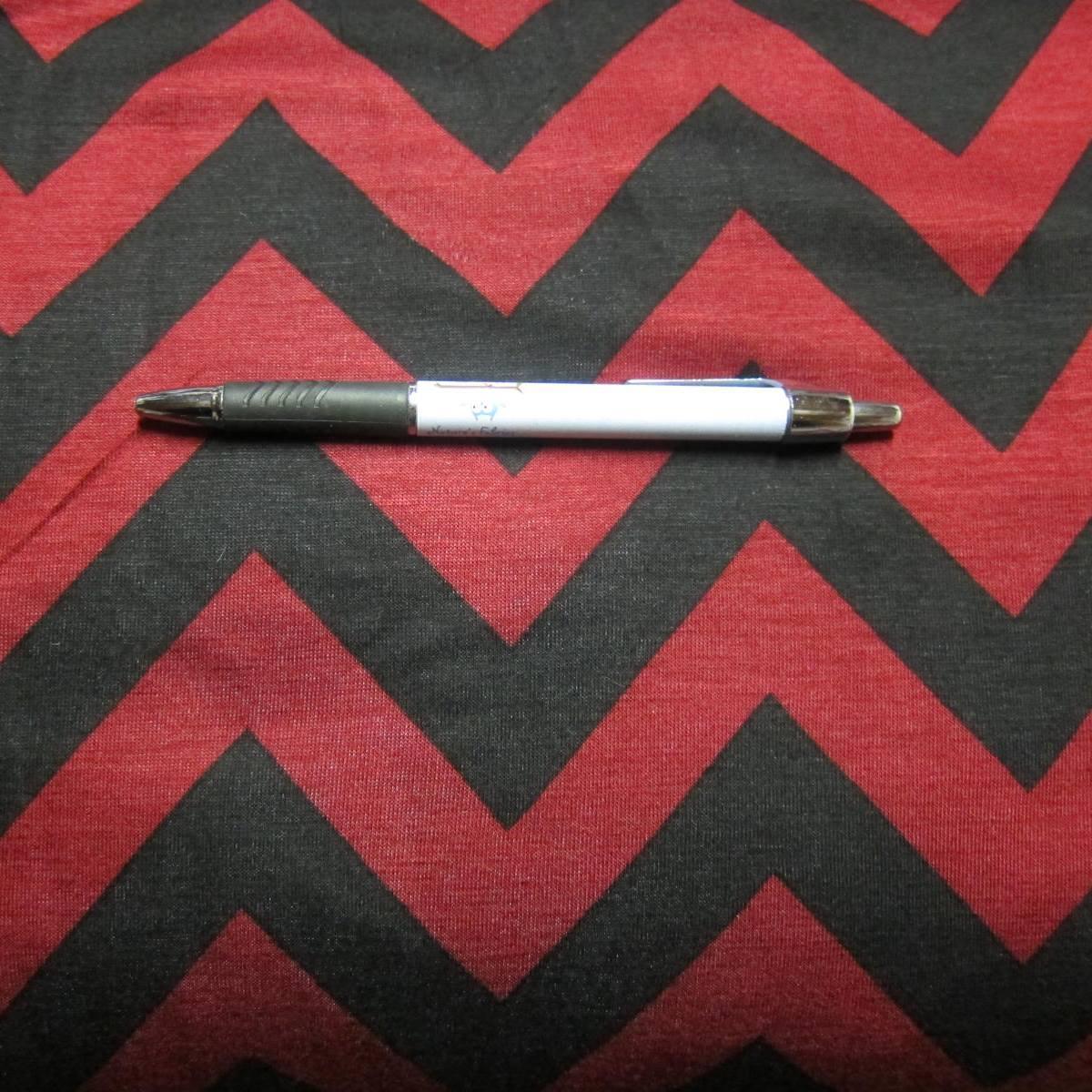 A white and grey pen resting on Nature's Fabrics red and black chevron pattern fabric.