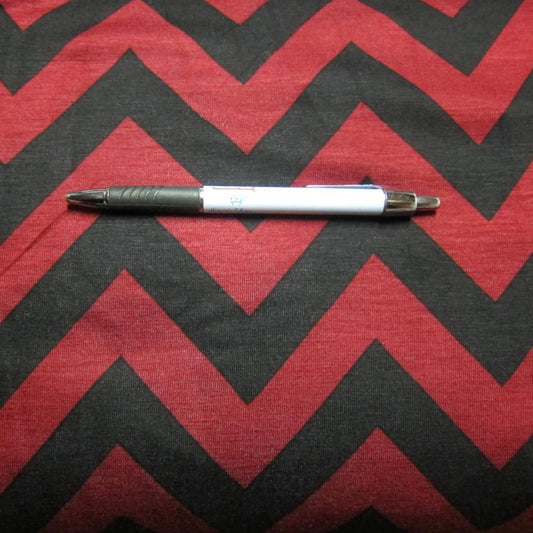 A white and grey pen resting on Nature's Fabrics red and black chevron pattern fabric.