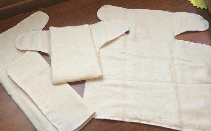 Reusable organic cotton menstrual pads from Nature's Fabrics on a wooden surface.