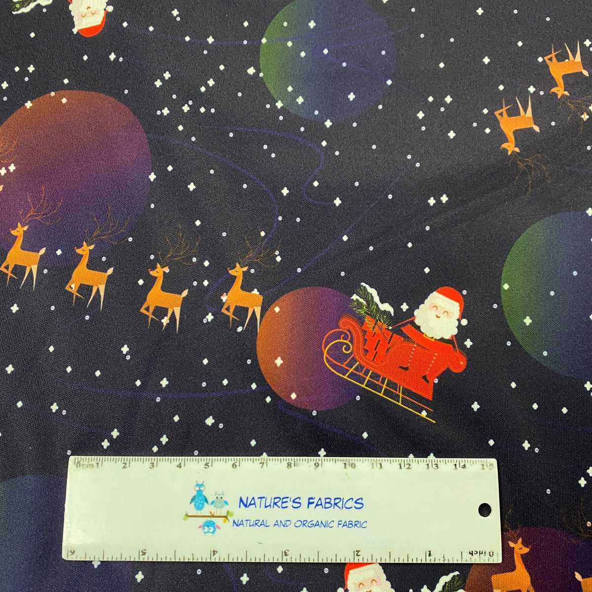 Nature's Fabrics Christmas themed fabric with Santa, reindeer, and planets on a dark background.