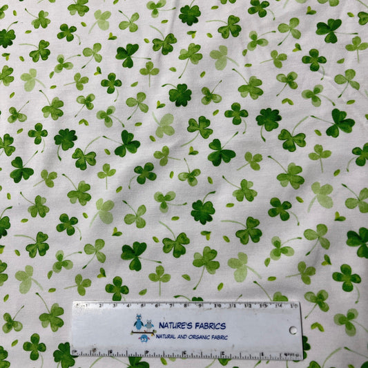 White Nature's Fabrics organic cotton fabric with a green shamrock pattern and a measuring scale.