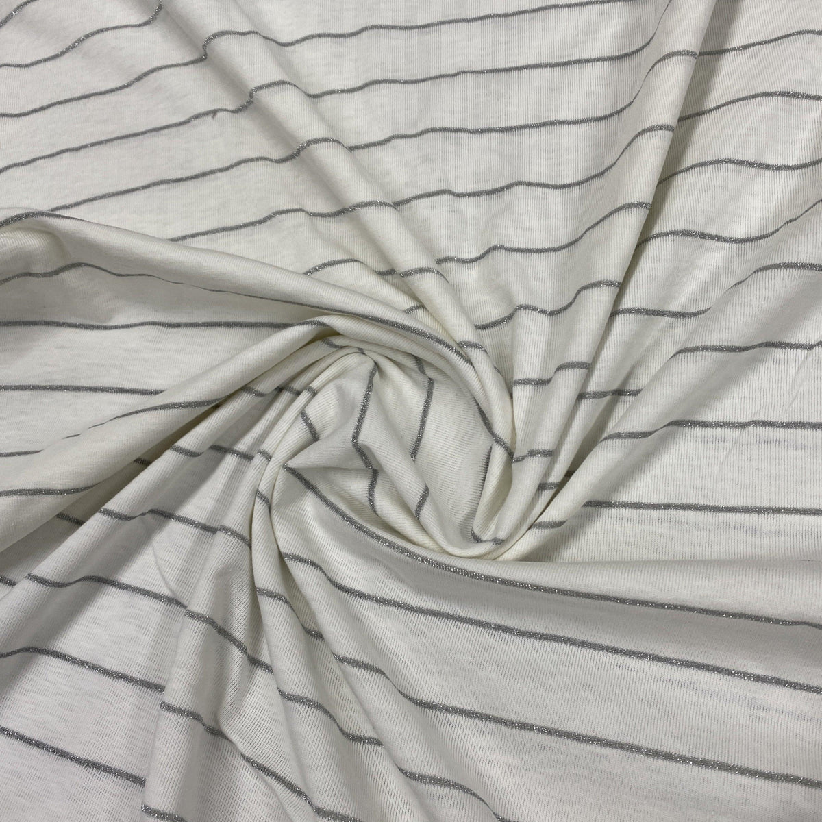 Nature's Fabrics white fabric with thin silver metallic stripes draped in a swirl.