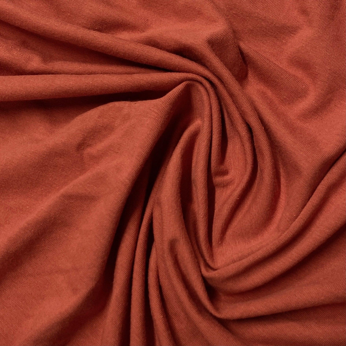 Close-up of draped terracotta orange organic cotton fabric from Nature's Fabrics