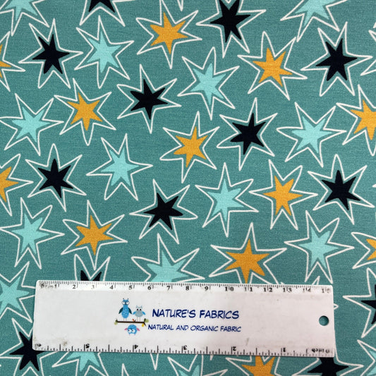 Nature's Fabrics teal organic cotton fabric with a multi-colored star pattern and a ruler.