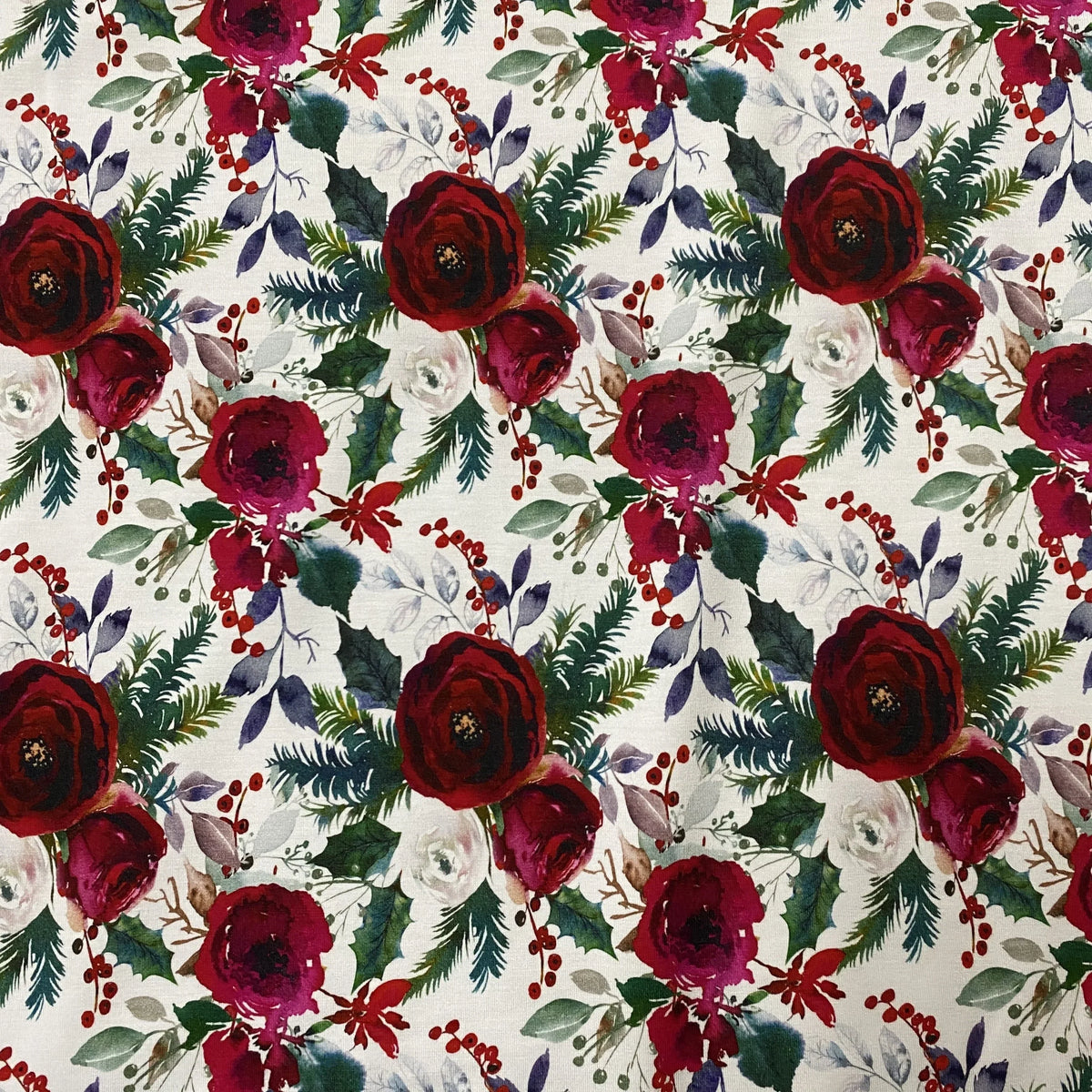 Nature's Fabrics floral print fabric with red roses and green evergreen foliage.