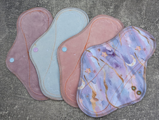 Reusable cloth pads in pastel colors and starry print, eco-friendly menstrual pads on gray background.