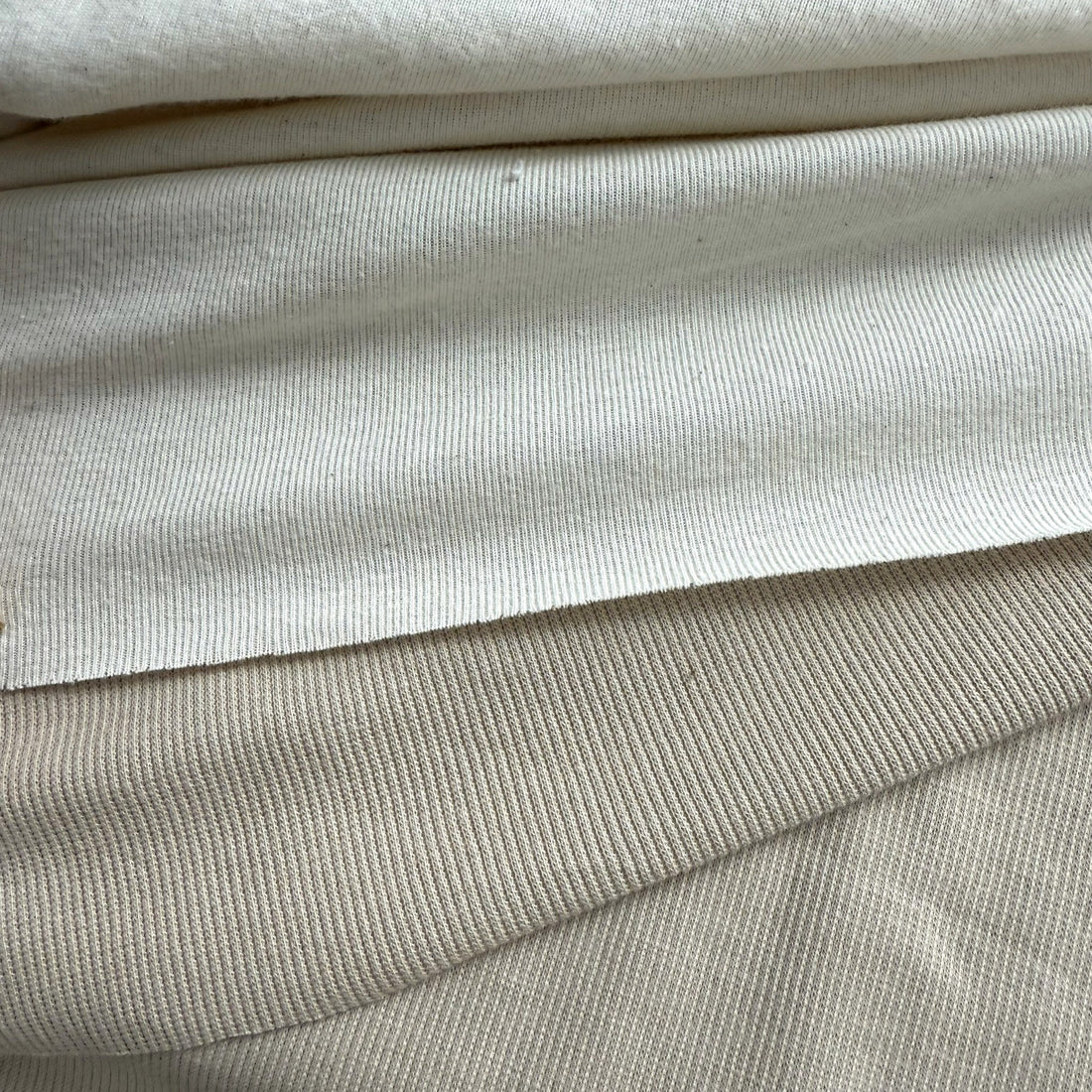 Close-up of rib knit and 2x1 rib knit fabric in neutral colors, showing stretch texture.
