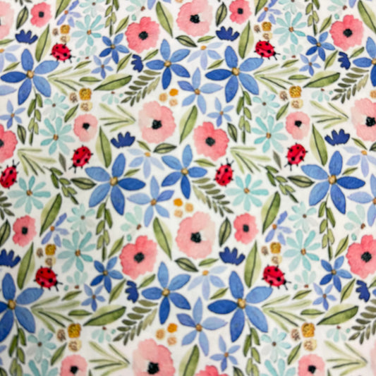 Floral fabric with pink, blue flowers, green leaves, and red ladybugs by Nature's Fabrics