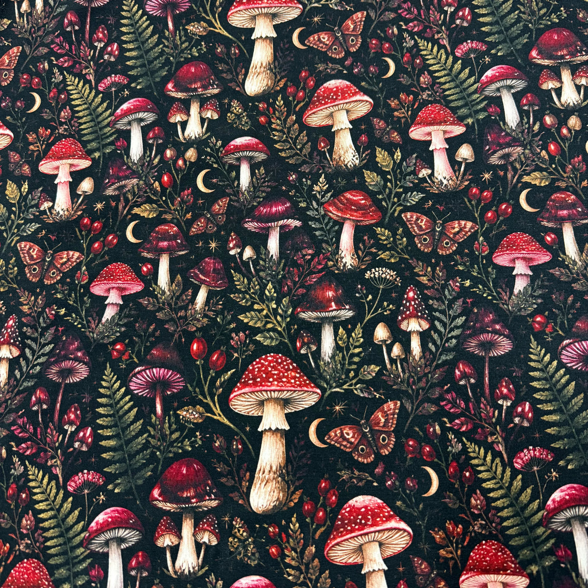 Nature's Fabrics mushroom pattern with red fungi, ferns, and butterflies on a dark background