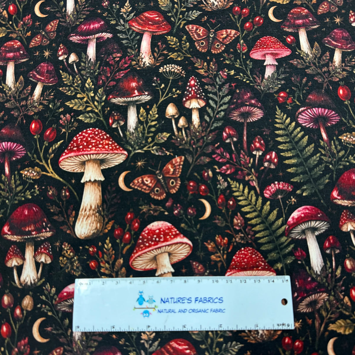 Nature's Fabrics organic cotton fabric with a red mushroom and forest motif.