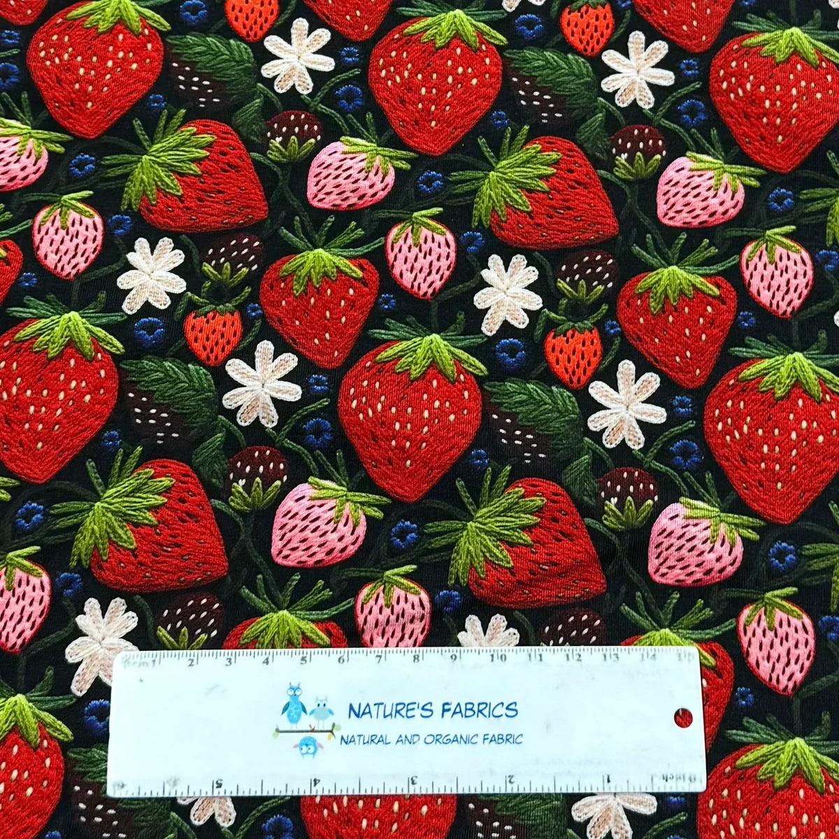 Strawberry print fabric by Nature's Fabrics — organic cotton with red, pink berries, green leaves, white flowers on black background