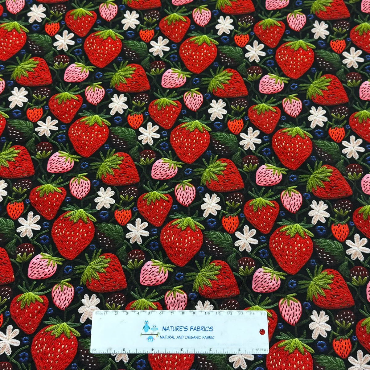 Strawberry print fabric by Nature's Fabrics — organic cotton with embroidered berries, flowers, and leaves on dark background