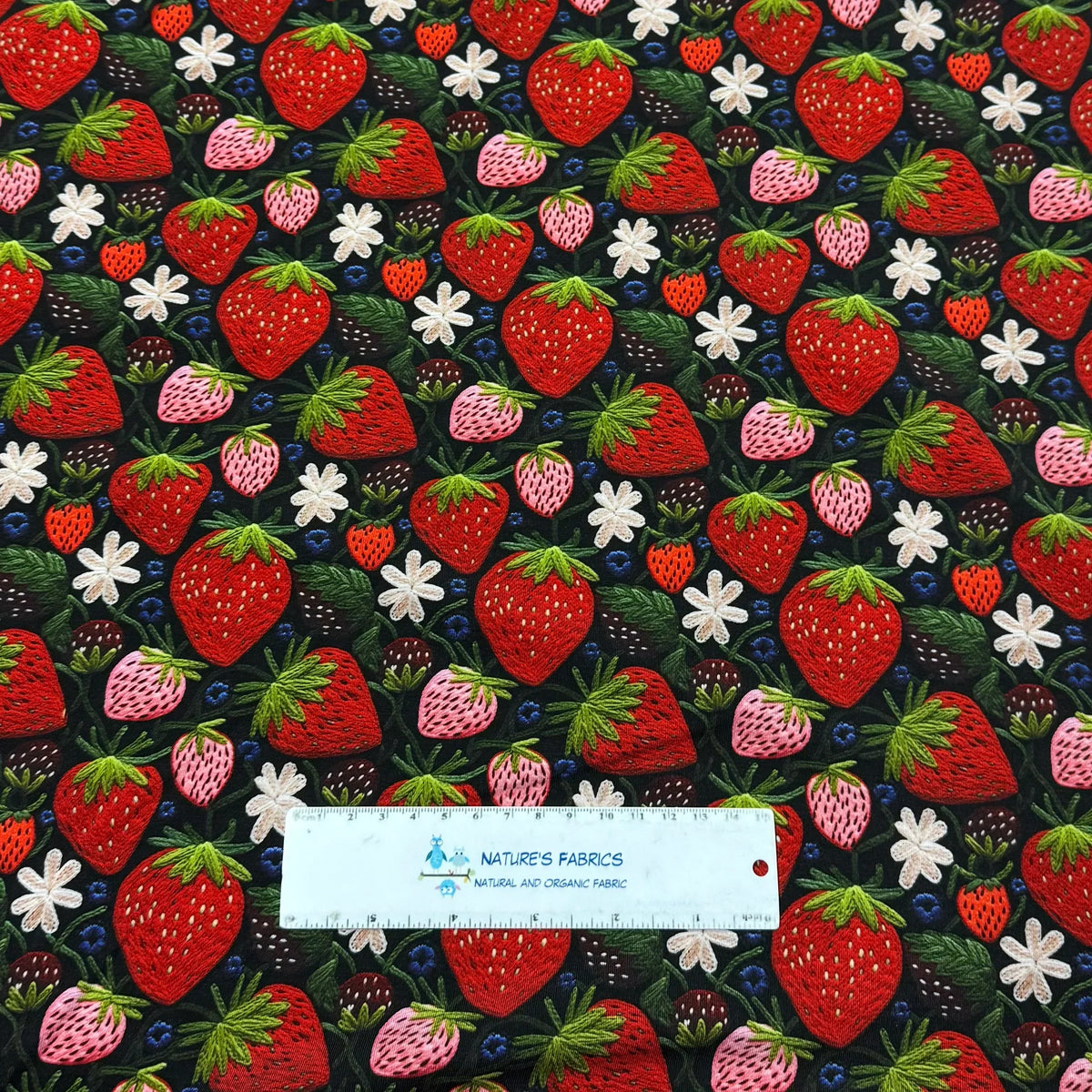 Strawberry print fabric by Nature's Fabrics — organic cotton with red, pink berries, white flowers, green leaves on black background
